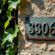 Plaque en métal ancienne avec le numéro 33806 sur un mur en pierre